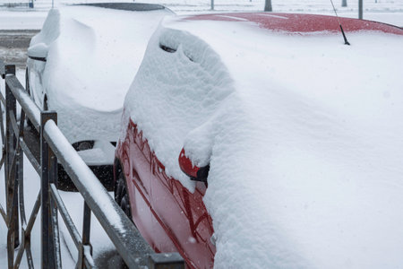 Parked cars lie buried under deep winter snow, capturing a quiet moment of heavy snowfall and seasonal urban stillness in morning light.の写真素材