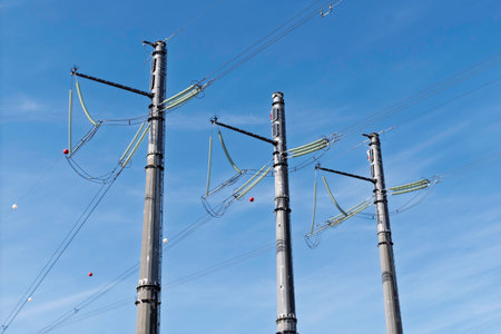 Tall power line towers rise against a clear blue sky, highlighting modern urban energy infrastructure and the scale of electrical networks.の写真素材