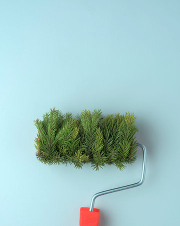 Paint roller with dense fir branches creates creative Christmas look on soft blue background with clean minimal compositionの写真素材