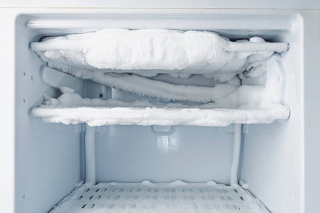 Heavily frosted freezer compartment waiting for proper defrost and cleaning, symbol of neglected appliance care at home todayの写真素材