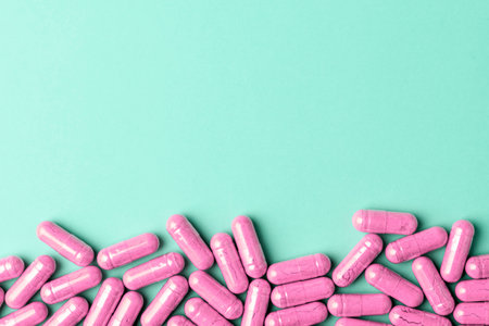 Pink supplement capsules form bottom border on mint background, calm medical banner with generous...