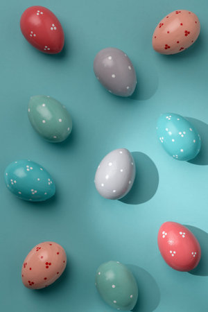 Pastel polka dot Easter eggs on turquoise background, partly sunlit with crisp shadows, minimal...