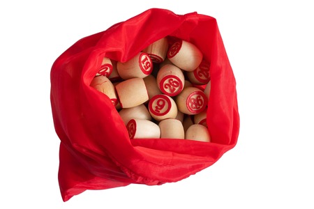 The old bingo Board game with wooden elements.wooden Lotto barrels in red bag on white isolated backgroundの写真素材
