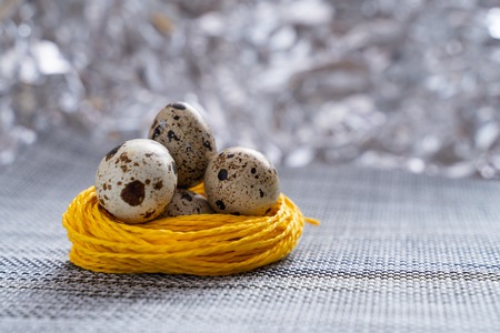 quail egg in a yellow nest on a gray table cloth close-upの写真素材