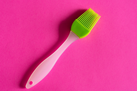green silicone brush with white handle on pink background top viewの写真素材