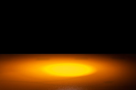 orange surface illuminated by warm light on black background. abstraction and design