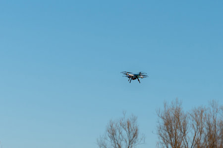 Drone with a camera flying in the air against the blue sky.technology and radio-controlled machines.