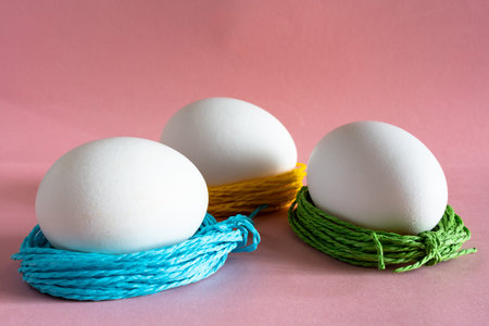 chicken egg on pink pastel background with beautiful decor of colored ropes. decor for Easter