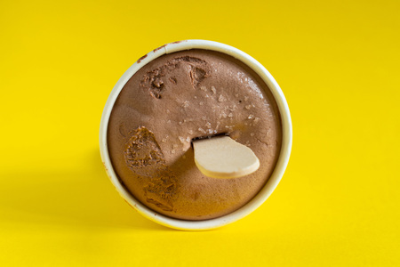 Paper cup with chocolate ice cream, just out of the freezer on the yellow backgroundの写真素材