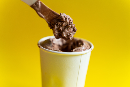 Paper cup with chocolate ice cream, just out of the freezer on the yellow backgroundの写真素材
