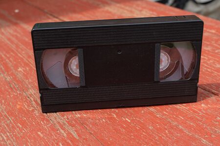 Old black VHS video tipe cassette on the red wooden tableの写真素材