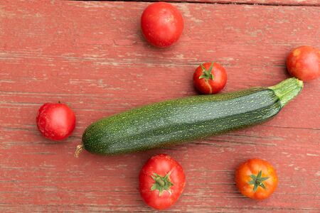 fresh vegetables green zucchini and red tomatoes on vintage wooden table top viewの写真素材