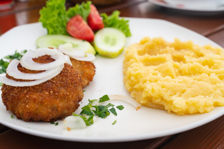 mashed potatoes with cutlet and salad on a white plate close-up. template for cafe menu or Wallpaper...