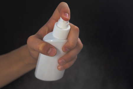 hand hygiene a teenager holds an antiseptic in his hands to protect against the virus on the black...