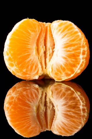 fresh tangerine on a black background with a beautiful reflection close upの写真素材