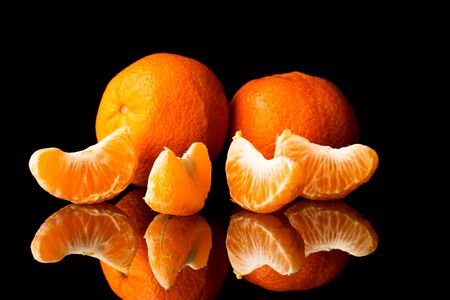 fresh tangerine on a black background with a beautiful reflection close upの写真素材