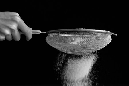 black and white picture of sifted flour through a sieve