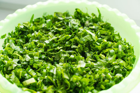 finely chopped green onions dill parsley in a plastic bowl close up