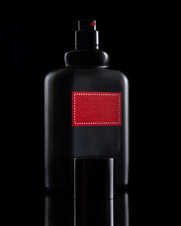 a black perfume bottle on a black table with a reflectionの写真素材