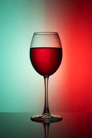a glass of red wine on a two-tone background with gradient and reflectionの写真素材