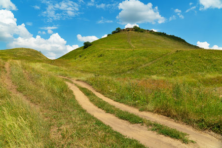 Landscape dirt road in the mountains under a cloudy sky in summer