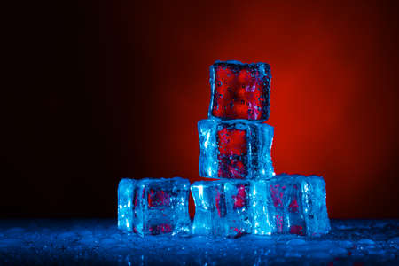 cold ice cubes with water drops on a red backgroundの写真素材