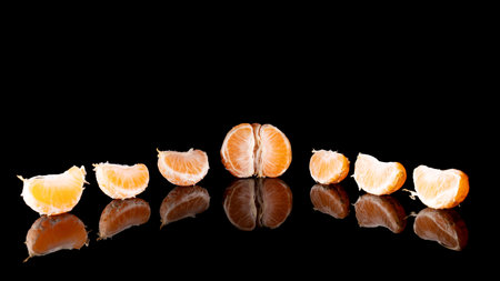 a ripe tangerine on a black table with a reflection. close-up