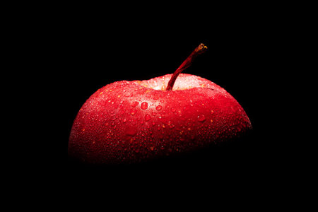 still life red apple with water drops on a black background close-up