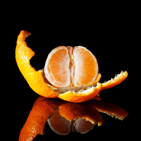 fresh juicy tangerine on a black table with reflectionの写真素材