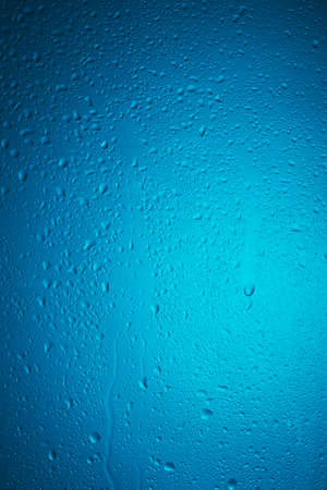 water drops on the glass surface on a blue gradient backgroundの写真素材