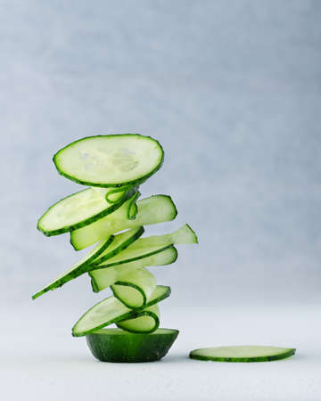 fresh cucumber cut into pieces on a knife blade on a light backgroundの写真素材