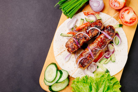 Grilled lula kebab on pita bread with vegetables on a dark backgroundの写真素材