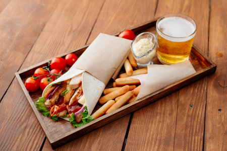Shawarma on a tray. Fast food. Eastern food. Street food. Shaverma, shawarma, shaurma, pita gyros. Shawarma lying on pita bread and decorated with tomatoes, bread sticks, sauce and beer.の写真素材