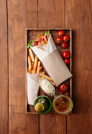 Shawarma on a tray. Fast food. Eastern food. Street food. Shaverma, shawarma, shaurma, pita gyros. Shawarma lying on pita bread and decorated with tomatoes, bread sticks, sauce and beer.の写真素材