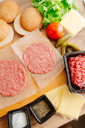 Ingredients for making burgers. Cooking burgers. Burger cutlets on a wooden board. Making burgers in your home kitchenの写真素材