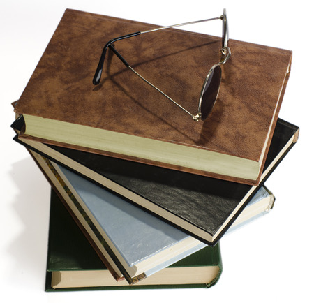 the pile of books with covers of different flowers lies on a light surface. On the top book glasses with dark glasses.の写真素材