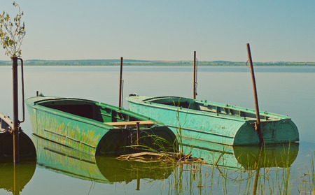 The boats attached by chains to iron probes on an equal water surface.の写真素材