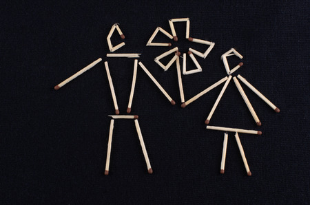 male and female figure laid out matchsticks on a dark knitted surfaceの写真素材