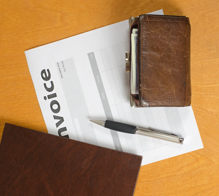 blank invoices and old leather and fountain pen lying on a light wooden surface.の写真素材