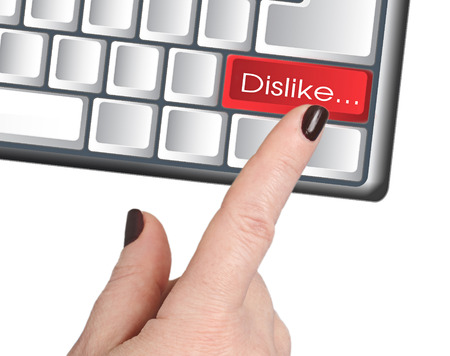Female hand presses the red button DISLIKE, painted keyboardの写真素材