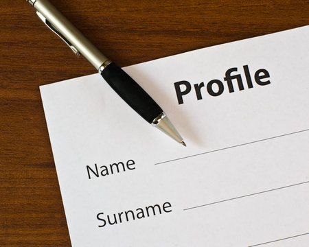 On a wooden table lies blank profile and pen