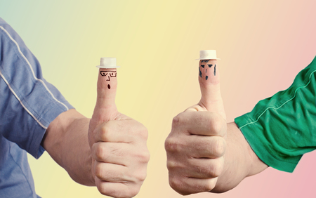 Two hands with raised thumbs. On your toes painted eyes and mouth, glasses, sideburns wearing a toy hatの写真素材