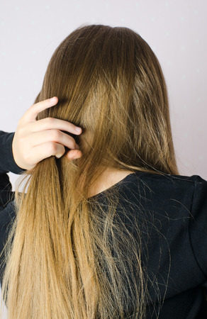 A young girl in a dark t-shirt combing Golden hairの写真素材