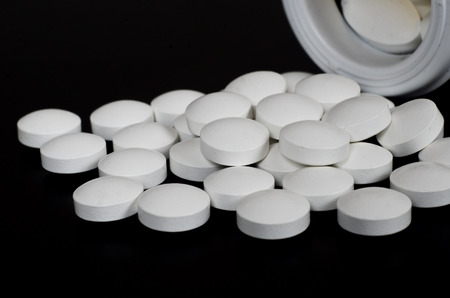 White round pill lying on the black surfaceの写真素材