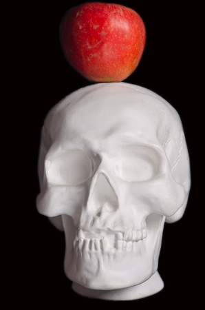 white imitation of a human head (skull) and red apple photographed on a black background 
の写真素材