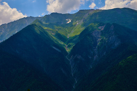Mountain river among the beautiful mountain hills of Svaneti. Beautiful shadows from the clouds in a...