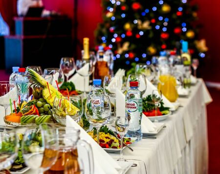 Served dishes to the table for holiday. Cutlery and food on white tablecloths in the restaurant. Design a festive Banquet.のeditorial素材