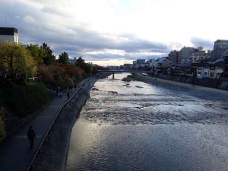 River and city in the evening. A lazy river and a Japanese city at sunset, the sky is cloudy.の写真素材