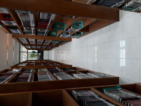 A corridor between brown wooden bookshelves. There are many books on the shelves.の写真素材