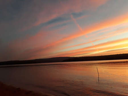 The evening sky by the dam with red and blue interspersed. There is a mountain behind.の写真素材